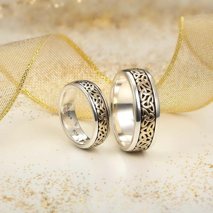 Two silver rings with intricate designs on a gold and white textured background