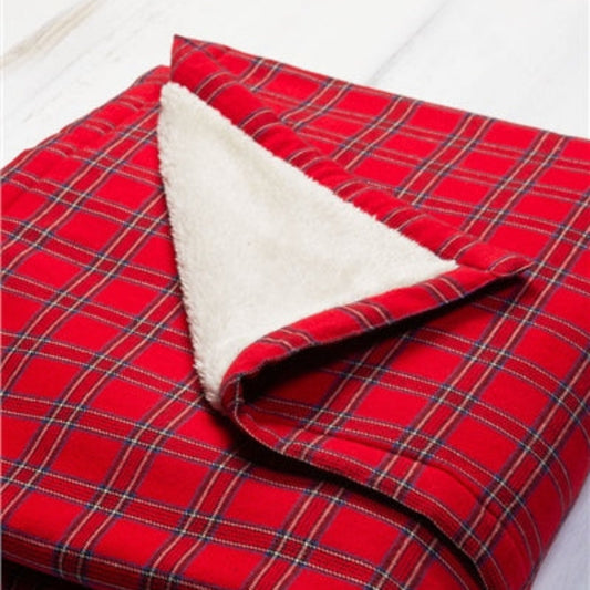 A red and blue plaid flannel throw draped over the back of a green chair, with a white fleece edge visible.
